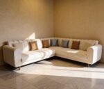 Serene beige L shape sofa with channel tufted back and wooden legs in modern living room setting
